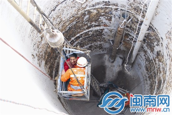 吊機(jī)將受傷工人和消防隊員吊出污水處理罐