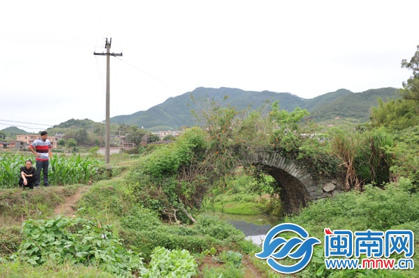 已廢棄的石拱橋，被野草覆蓋，下有溪流，村民稱此路