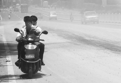 摩托車司機只能一手捂著口鼻，一手抓著扶手，快速闖