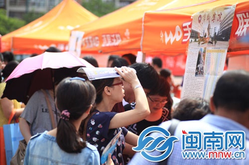 海都咨詢會現(xiàn)場，一名家長頂著烈日看學校信息