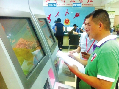 工作人員指導(dǎo)李建才在終端機(jī)上填寫材料。