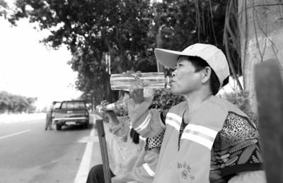 酷暑難耐，清潔工在小憩時為自己補(bǔ)充水分。本報記者